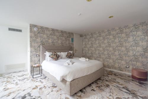 una camera con un grande letto in una stanza con carta da parati di Duomo Smart Suites a Milano