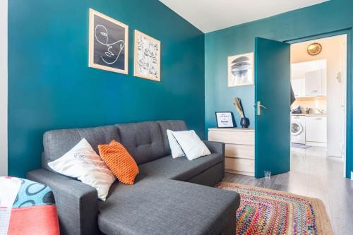 uma sala de estar com um sofá e uma parede azul em Beau et Cosy studio - 8min Paris em Rosny-sous-Bois