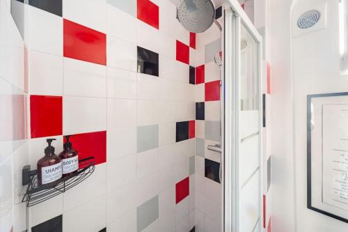 uma casa de banho com azulejos vermelhos e brancos na parede em Beau et Cosy studio - 8min Paris em Rosny-sous-Bois