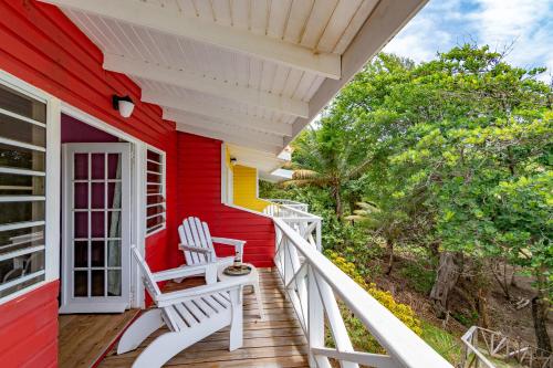 a red house with two white chairs on a porch at Cabier Ocean Lodge in Crochu