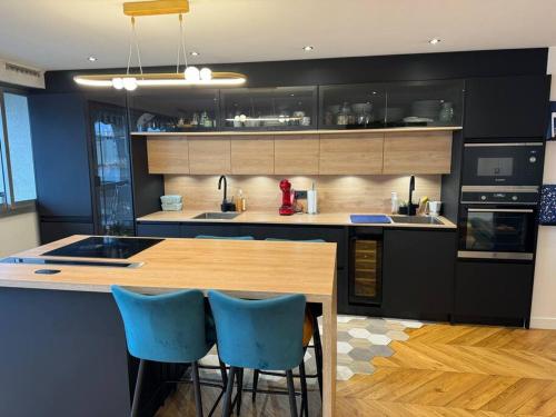 une cuisine avec une table en bois et des chaises bleues dans l'établissement Appartement cosy vu Tour Eiffel, à Courbevoie