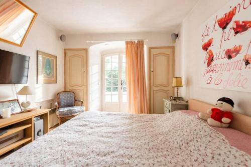 a bedroom with a large bed with a teddy bear sitting on it at Villa Provençal StTropez Ramatuelle Pampelonne beach in Saint-Tropez