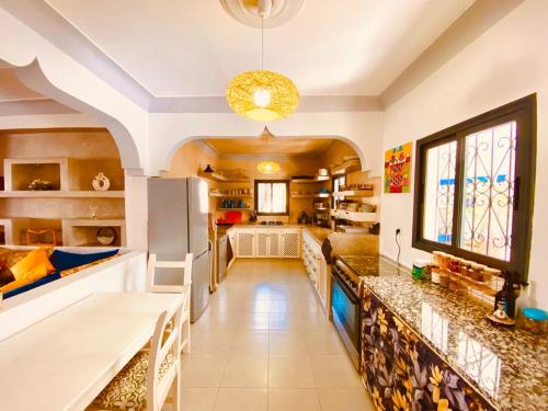 La cuisine est équipée de comptoirs blancs et d'un réfrigérateur. dans l'établissement Riad Ghazal, à Essaouira