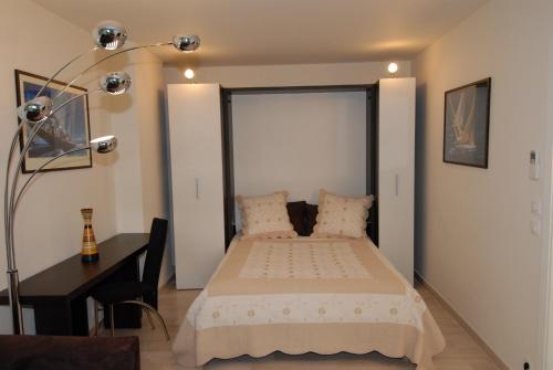 1 dormitorio con cama, escritorio y lámpara en IPANEMA Residence Le Vendome, en Cannes
