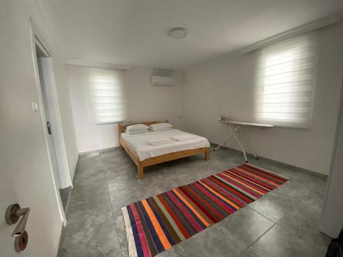 um quarto com uma cama, um tapete e 2 janelas em Mavi Boncuk em Muğla