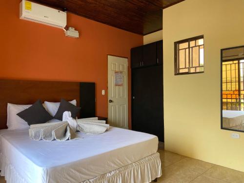 a bedroom with a white bed with an orange wall at Hospedaje Coffee and cocktails in Estelí