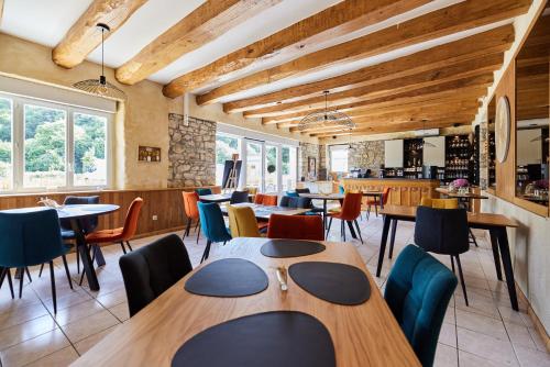 ein Restaurant mit Holztischen, Stühlen und Fenstern in der Unterkunft Laouen Blavezh'ti in Saint-Barthélemy