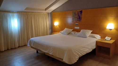 a bedroom with a large white bed and two lamps at Ruta Jacobea in Lavacolla