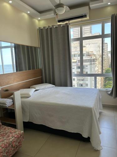 a bedroom with a bed and a large window at COPACABANA RIO PRAIA 18 in Rio de Janeiro