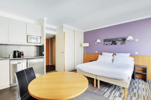 Cette chambre comprend un lit, une table et une cuisine. dans l'établissement Le CHARMANT Paris Expo Appart'hotel Adagio 4', à Issy-les-Moulineaux