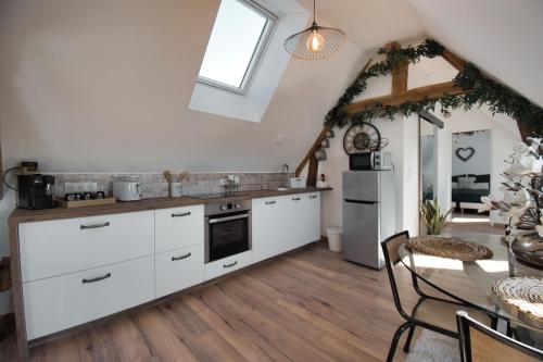 une cuisine avec des armoires blanches et une table et une salle à manger dans l'établissement LE RELAIS DES CALECHES - l'Appartement 