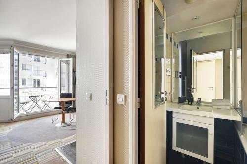 une salle de bain avec un lavabo et un grand miroir dans l'établissement Le CHARMANT Paris Expo Appart'hotel Adagio 4', à Issy-les-Moulineaux