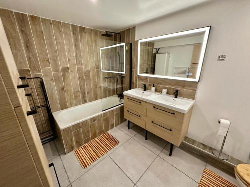 ein Badezimmer mit einem Waschbecken, einer Badewanne und einem Spiegel in der Unterkunft Maison de ville in Concarneau