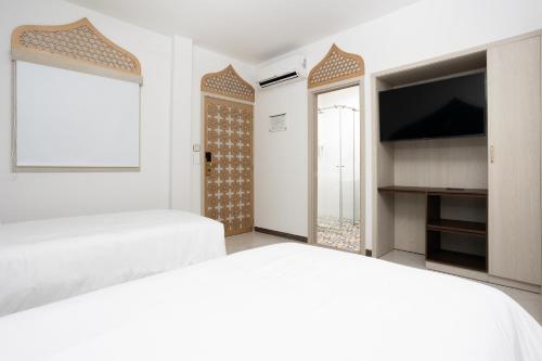 a bedroom with two beds and a flat screen tv at Prixma Hotel in San Andrés