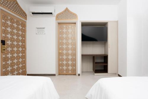 a bedroom with two beds and a door with a television at Prixma Hotel in San Andrés