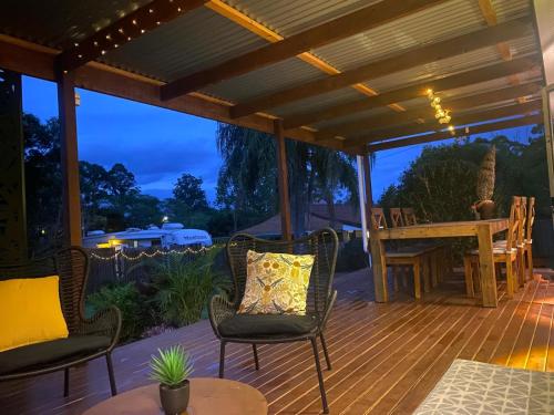 a wooden deck with chairs and a wooden table at Quirky little 2 bedroom in quiet cul-de-sac in Kempsey