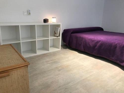 a bedroom with a purple bed and a white shelf at Villa Loba. Apartamento en casa rural. in Facinas