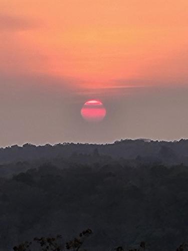 a sunset with the sun in the sky over the mountains at Hacienda en Los Volcanes in Hacienda Guayabo