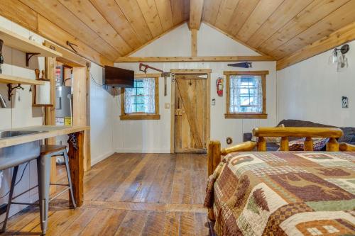 ein Schlafzimmer in einem winzigen Haus mit einem Bett und einer Küche in der Unterkunft Rustic Wellston Cabin with Fire Pits and ATV Trails! in Hamden