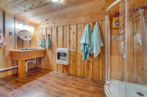 een badkamer met houten wanden, een douche en een wastafel bij Rustic Wellston Cabin with Fire Pits and ATV Trails! in Hamden