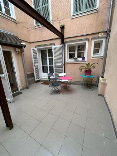 un patio avec des chaises et une table devant un bâtiment dans l'établissement Le Montagnard, RDC 1 chambre, à Chartres
