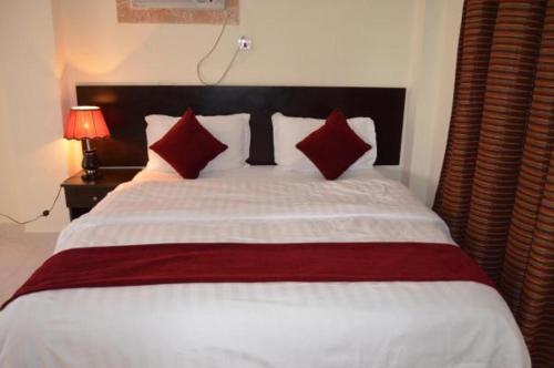 ein Schlafzimmer mit einem großen weißen Bett mit roten Kissen in der Unterkunft شقق آن للشقق المخدومة in Al-Dschubail