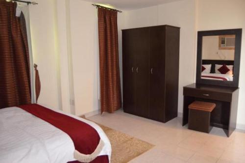 Schlafzimmer mit einem Bett, einer Kommode und einem Spiegel in der Unterkunft شقق آن للشقق المخدومة in Al-Dschubail