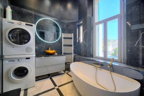 a bathroom with a tub and a washing machine at Luxury 2-floor Flat (95 sqm) near Hotel Martinez in Cannes