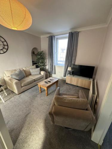 a living room with a couch and a table at Scott Street Modern Flat in Galashiels
