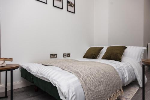 a white bedroom with a large bed with green pillows at Modern and Comfy in City Centre PS4 , Free Parking ,Walking Distance To Bus, Train Stations And Shopping Centres in Leicester