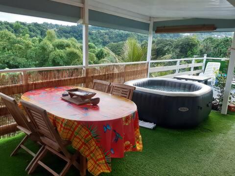 un patio con una mesa y una bañera en una terraza en Sous le Bois d'inde, en Saint-Joseph