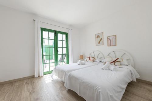 a white bedroom with a large bed and a window at Casa Moure in Costa Teguise