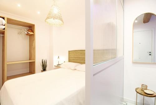 una camera con letto bianco e specchio di Piso con encanto en la playa a Villajoyosa