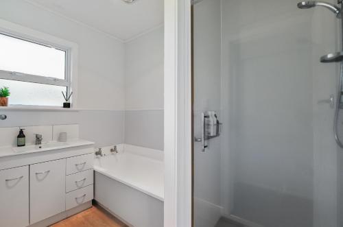 a white bathroom with a tub and a sink at Home Base in Rotorua