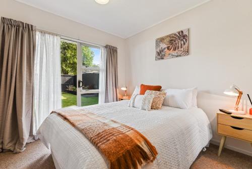 a white bedroom with a bed and a window at Home Base in Rotorua