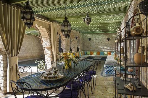 patio ze stołem i krzesłami oraz basenem w obiekcie Riad des 1001 Fleurs w mieście El Arba