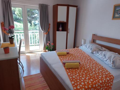 a bedroom with a bed with an orange and white blanket at Apartments Zvonimir in Hvar