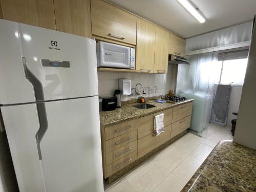 uma cozinha com um frigorífico branco e armários de madeira em Jardim Botânico Curitiba em Curitiba