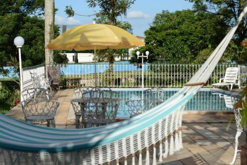 a hammock with a table and chairs next to a pool at Ninho dos Passaros Penedo RJ in Penedo