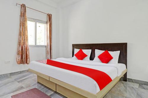 a bedroom with a large bed with red pillows at Collection O Cosmos Resort in Rājpur