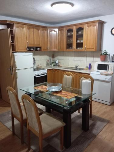 cocina con mesa de cristal con sillas y electrodomésticos blancos en Dženana, en Sarajevo