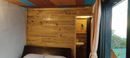ピエデクエスタにあるCabañas de la lomaの木製の壁のベッドルーム(ベッド1台、シンク付)