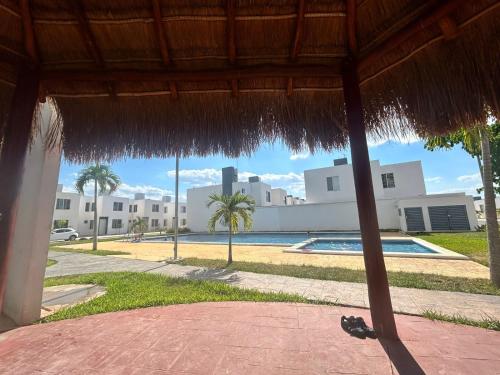 a view of a resort with a pool and a straw umbrella at Casa Paraíso tropical in Techoh