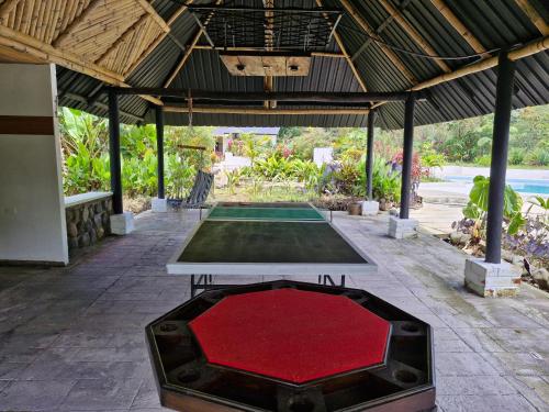 una mesa de ping pong en un pabellón con una alfombra roja en Camping La Penal, en Cumandá