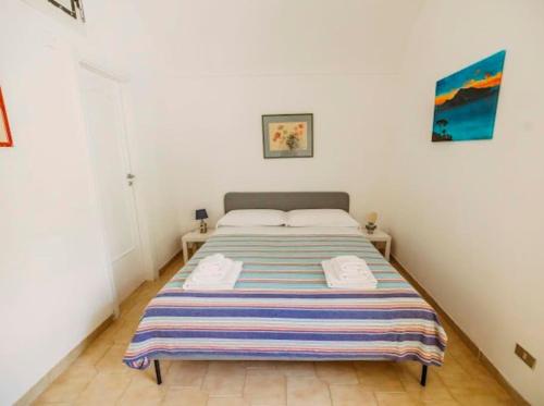 a bedroom with a bed with a striped blanket on it at Casa Silvana, Capri - Relaxando en el verde in Capri