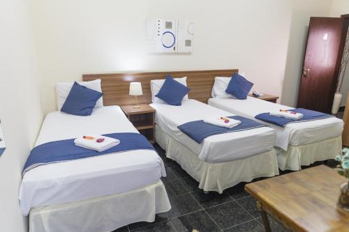 a room with three beds with blue and white pillows at VILLAGE GOLDEN HOTEL in Jales