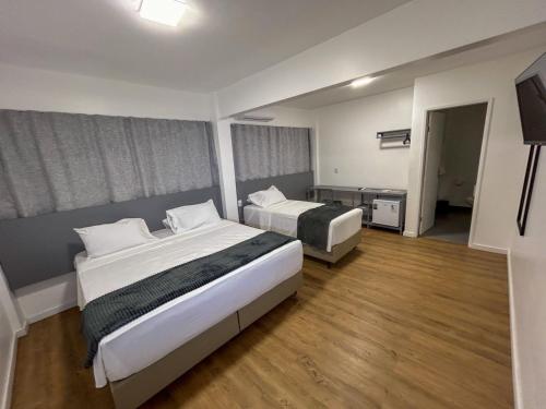 um quarto de hotel com duas camas e uma televisão de ecrã plano em Hotel do Vale em Campina Grande