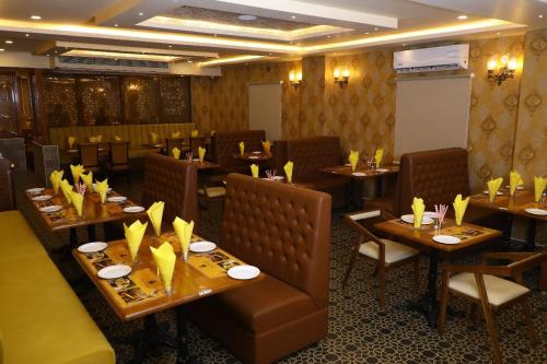 a restaurant with wooden tables and chairs with yellow napkins at Hotel Windsor Plaza in Hyderabad