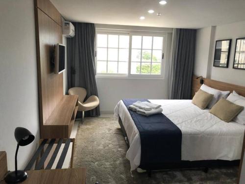 een slaapkamer met een bed, een bureau en een raam bij Flat Granja Brasil Resort in Petrópolis