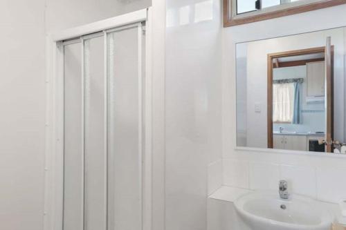 La salle de bains blanche est pourvue d'un lavabo et d'un miroir. dans l'établissement Reflections Lake Burrendong - Holiday Park, à Mumbil
